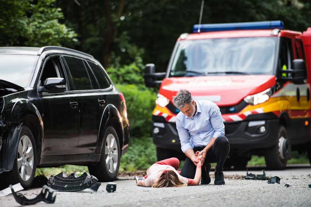 A personal injury lawyer in Reno, NV from Joey Gilbert Law is needed by this man helping a young woman lying unconscious on the road after a car accident.