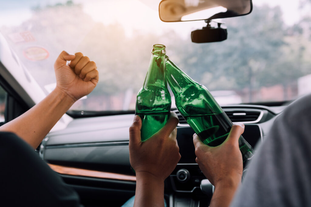 criminal defense attorney reno Two male friends are celebrating in the car while they are clinking beer bottle together Joey Gilbert Law Reno NV