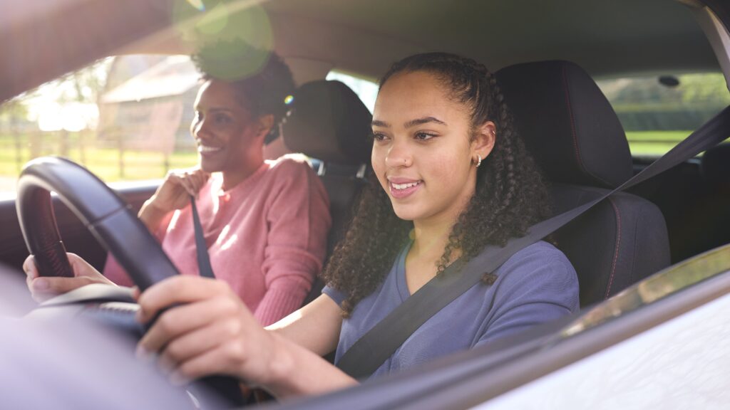 Teen driver in car with a parent in the passenger seat, discussing safe driving practices on a Nevada highway.